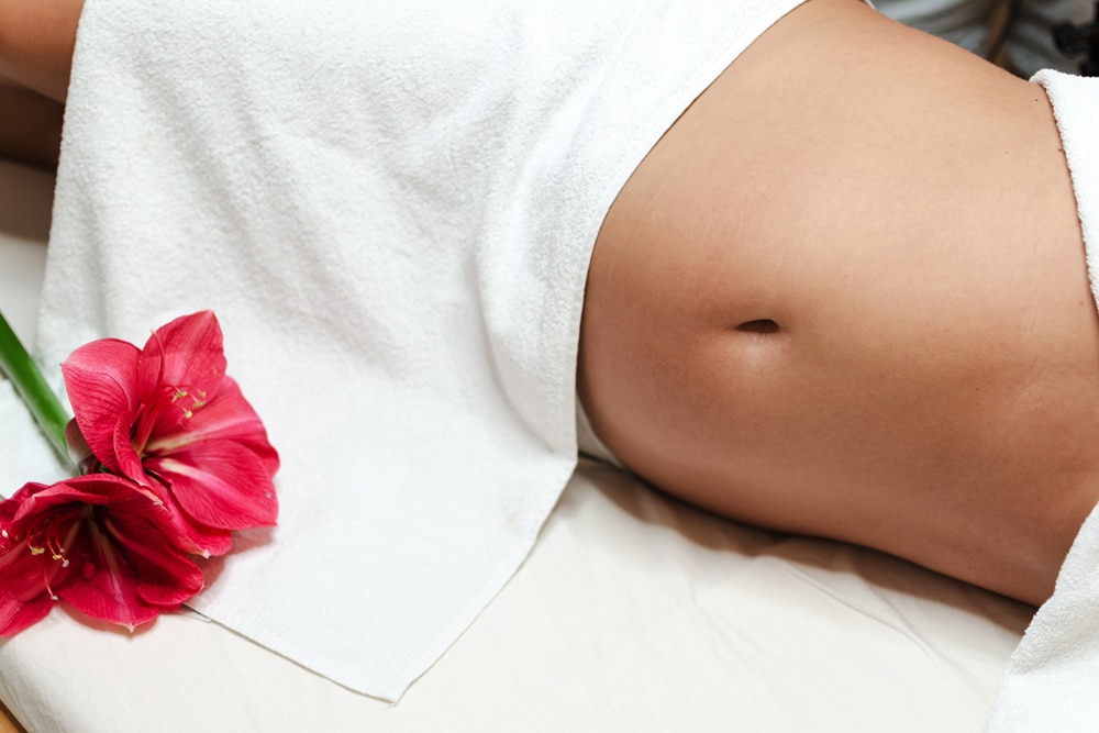 A Pregnant Woman on a bed with a red flower beside her